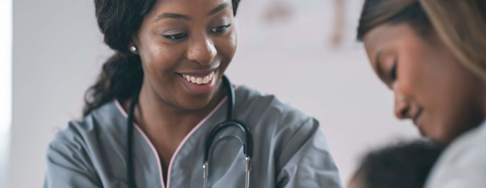 Black Female nurse checking baby in wellness medical exam