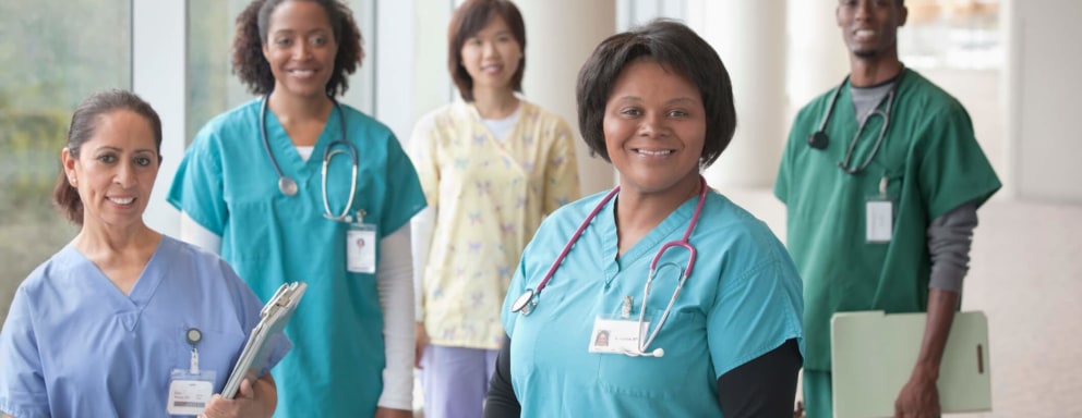 A diverse group of five male and female nurses standing in a hospital hallway