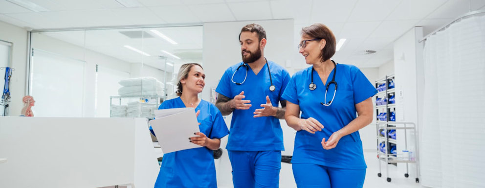 Three nurses walking and talking together in a hospital